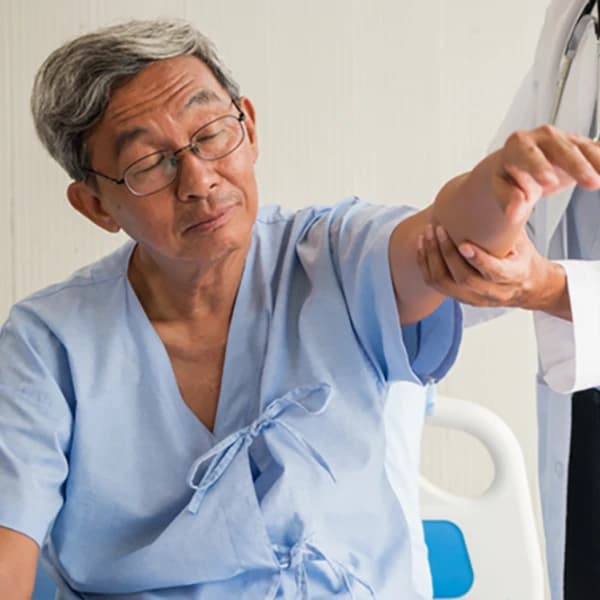 Doctor examining arm of elderly patient