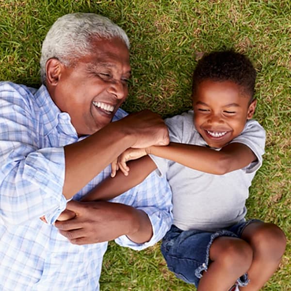 Grandfather and grandson play lying on grass