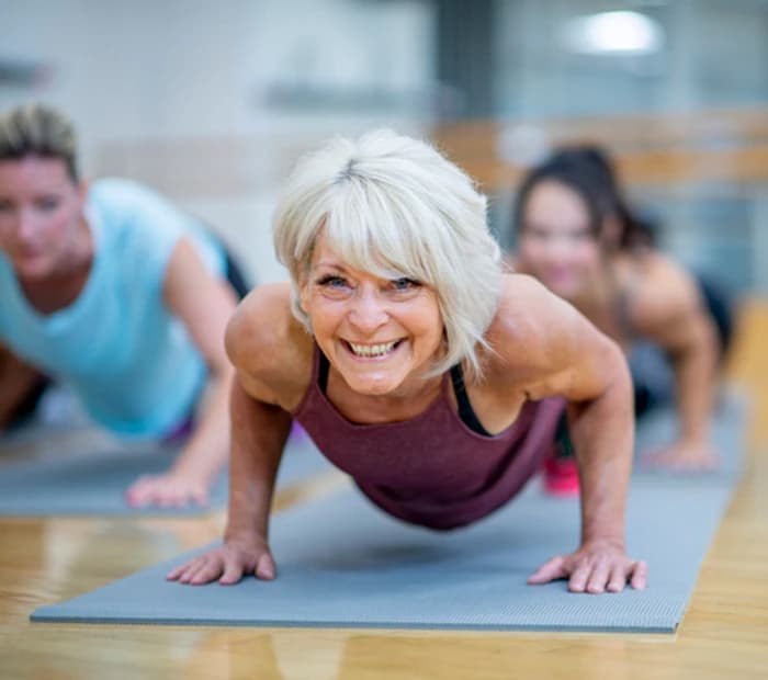 Senior Woman in Fitness Class in a Plank Pose Smiling